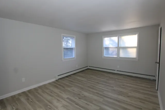 an empty room with wooden floor and windows