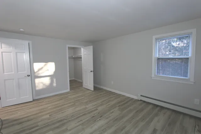 a view of an empty room with a window and wooden floor