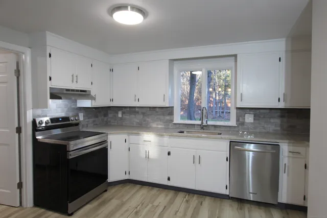 a kitchen with granite countertop white cabinets stainless steel appliances and window