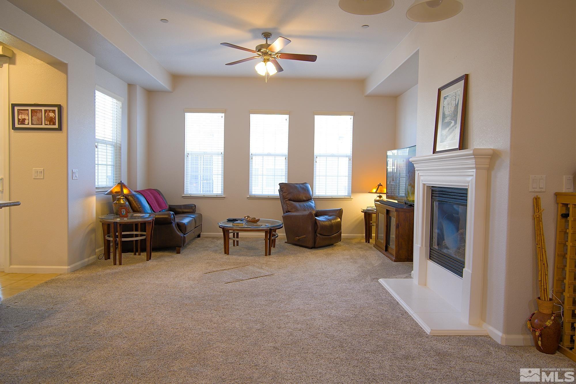 1895 Wind Ranch Road, Unit C Reno, NV 89521 - Photo 3 of 18 a living room with furniture a fireplace and a flat screen tv