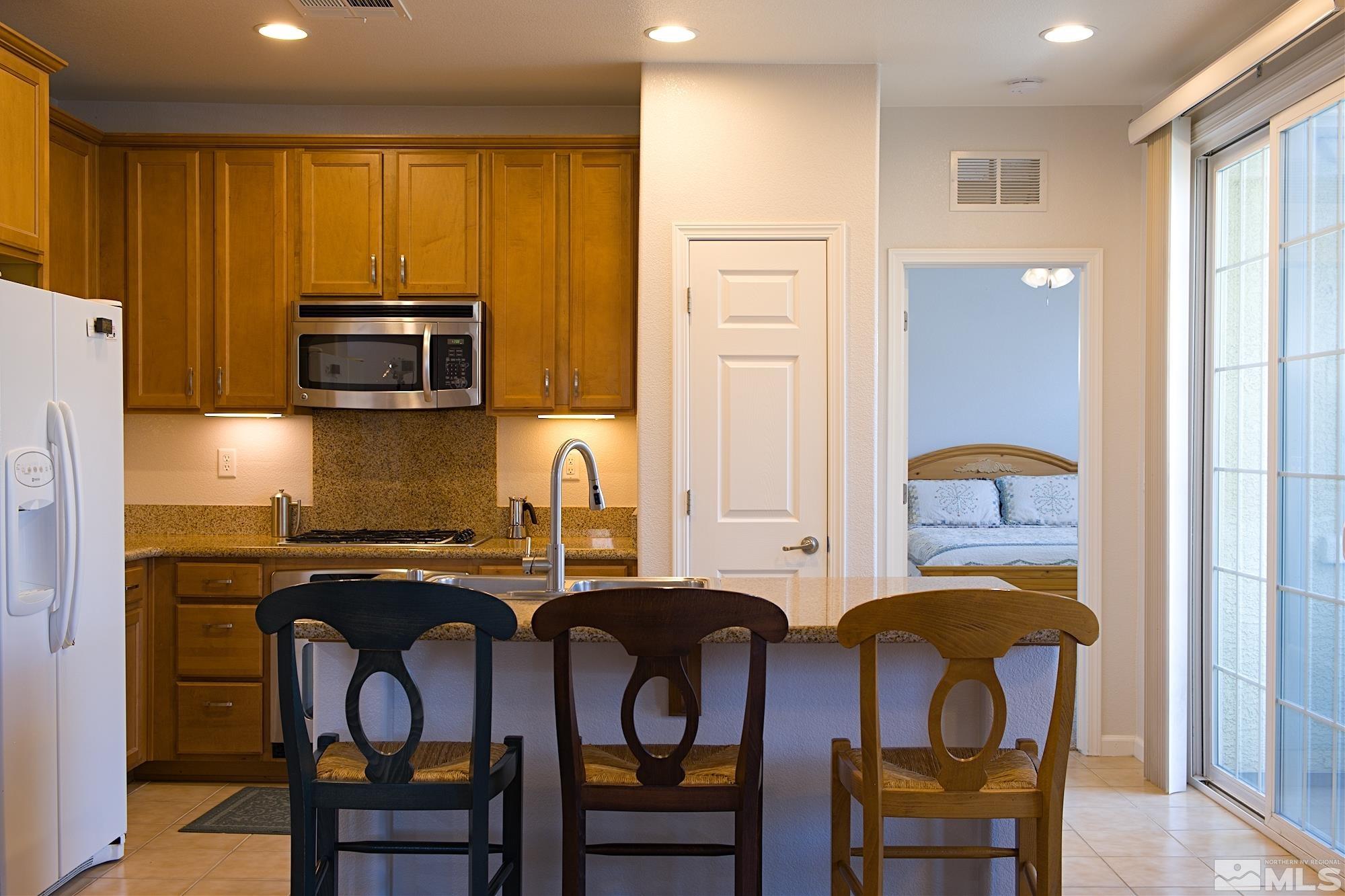 1895 Wind Ranch Road, Unit C Reno, NV 89521 - Photo 6 of 18 a kitchen with stainless steel appliances granite countertop a table chairs sink refrigerator and microwave