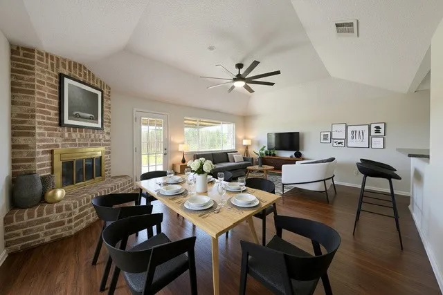 a view of a dining room with furniture a fireplace and wooden floor
