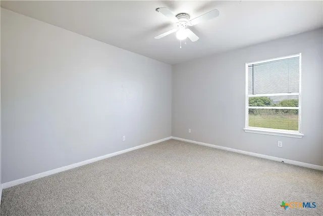 an empty room with a window and a fan