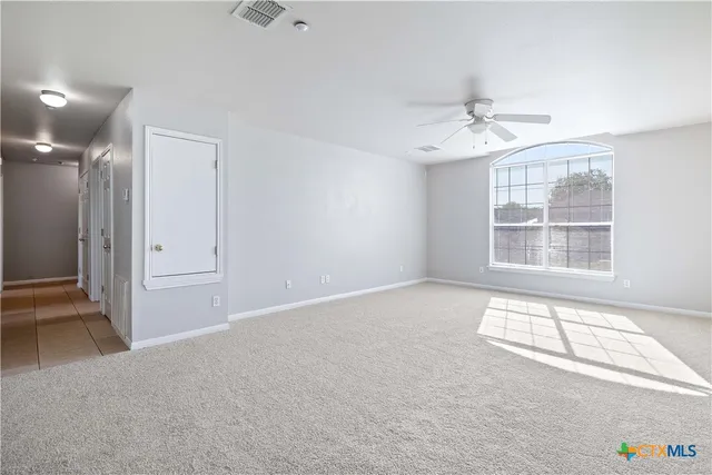 an empty room with windows and ceiling fan