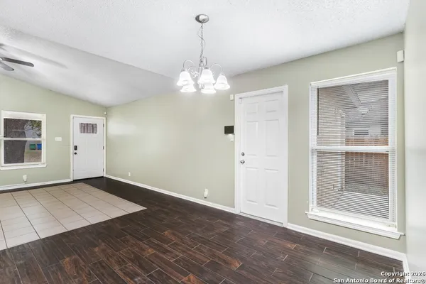 an empty room with wooden floor cabinet and windows