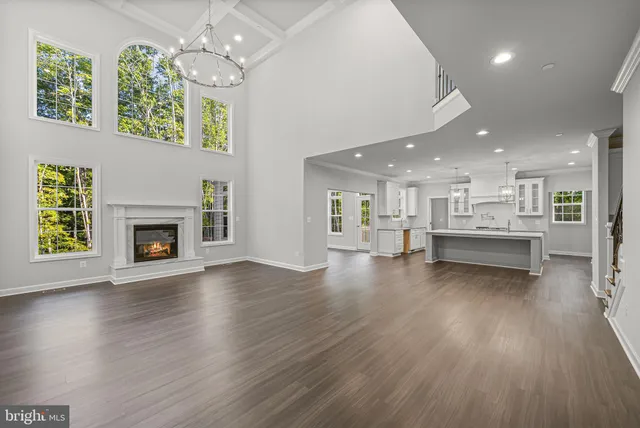 an empty room with wooden floor a kitchen view and a fireplace