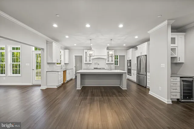 a large white kitchen with a center island wooden floor and stainless steel appliances
