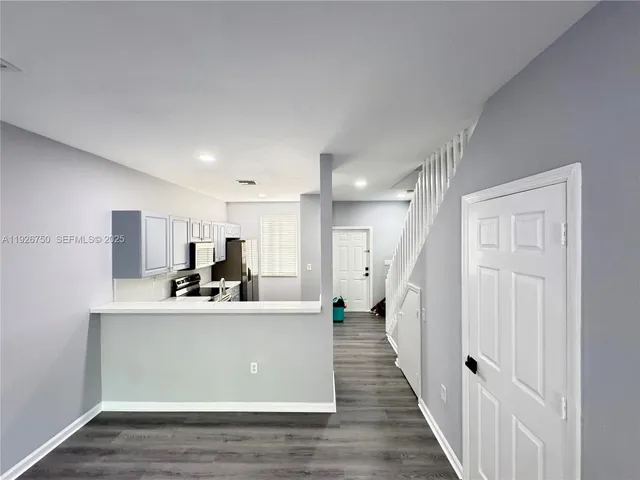 a view of a kitchen with kitchen island a sink wooden floor and living room view