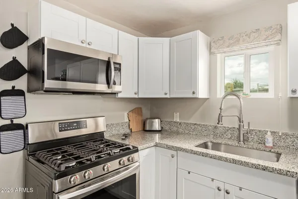 a kitchen with granite countertop a stove sink and cabinets