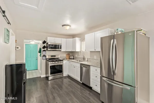 a kitchen with stainless steel appliances a refrigerator a stove top oven a sink and cabinets
