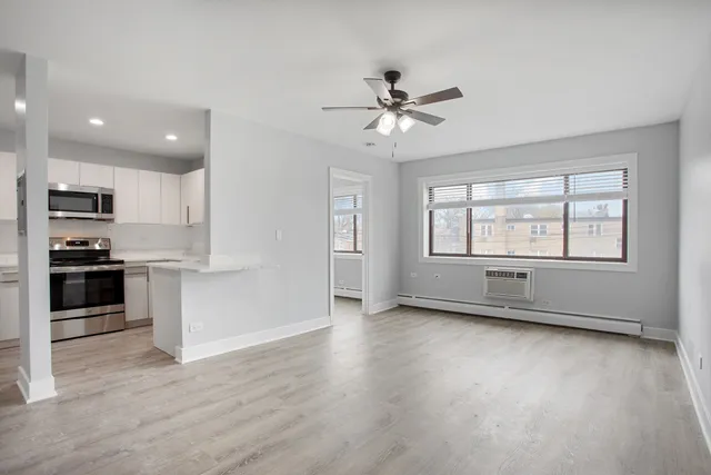 a view of an empty room with a kitchen and a window