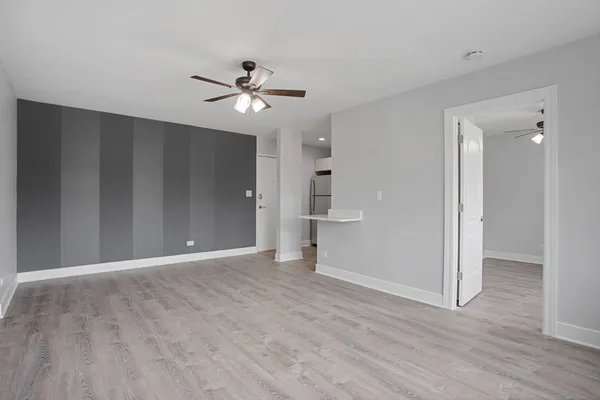 a view of empty room with wooden floor and ceiling fan
