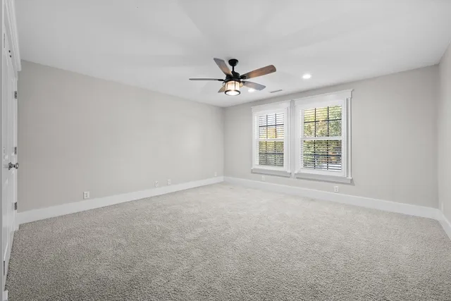 an empty room with windows and ceiling fan