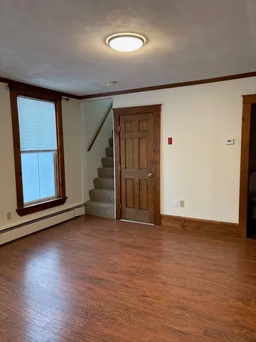a view of an empty room with wooden floor and stairs