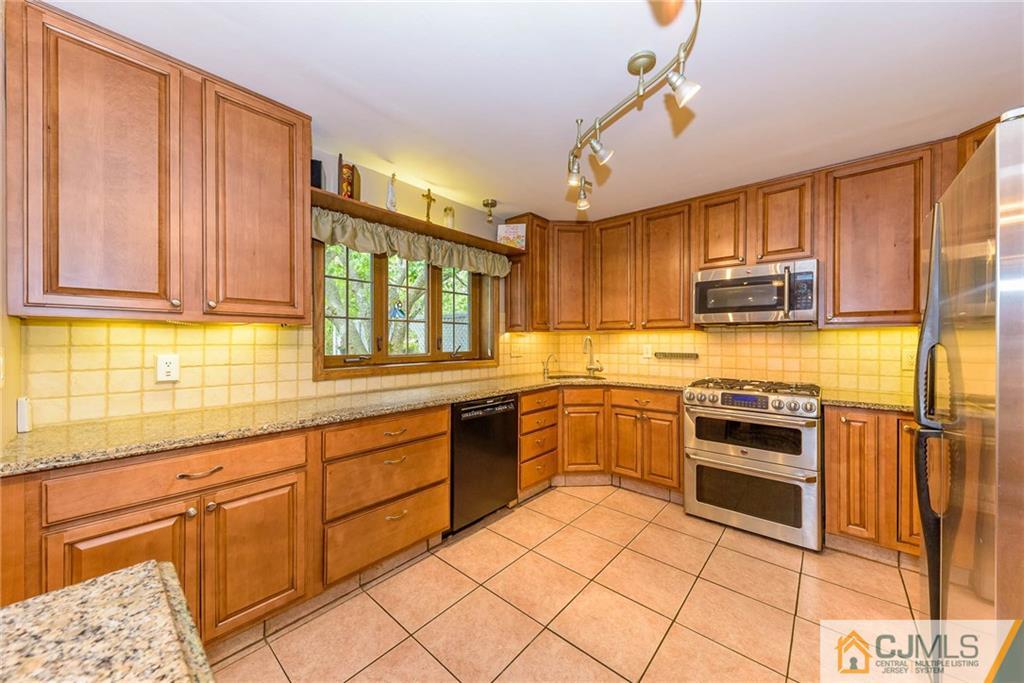 23 Covered Bridge Road Branchburg, NJ 08853 - Photo 7 of 25 a kitchen with stainless steel appliances granite countertop a stove top oven a sink dishwasher and cabinets with wooden floor