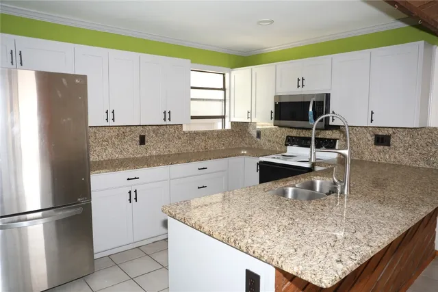 a kitchen with stainless steel appliances granite countertop a sink refrigerator and microwave