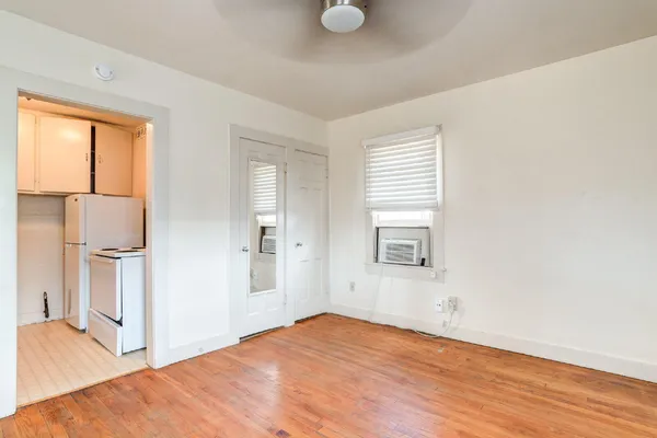 a view of empty room with wooden floor and fan