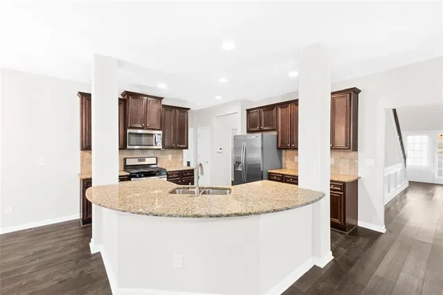 a kitchen with stainless steel appliances granite countertop a refrigerator a stove and a wooden floors