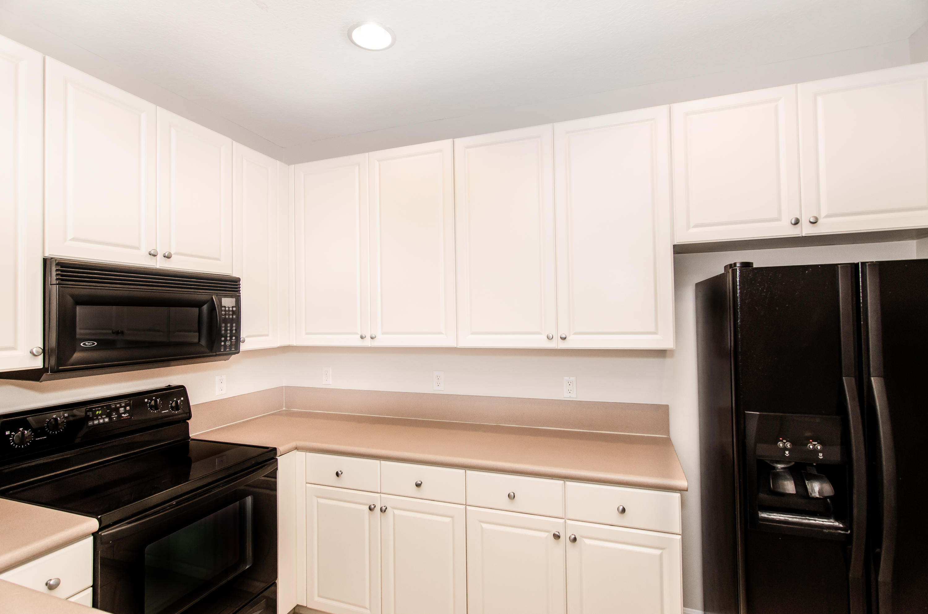 4281 East Main Street Jupiter, FL 33458 - Photo 4 of 37 a kitchen with granite countertop white cabinets and black appliances