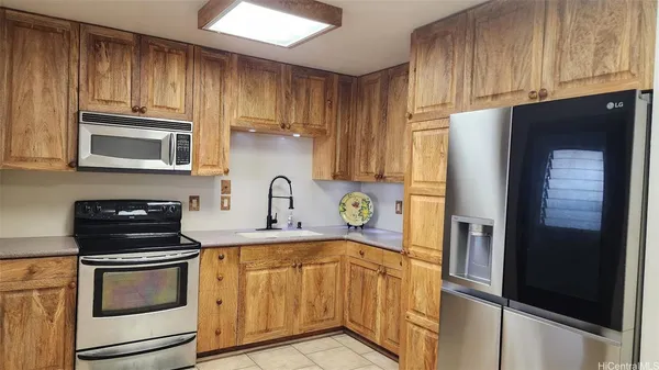 a kitchen with stainless steel appliances granite countertop a refrigerator stove and sink with wooden cabinets