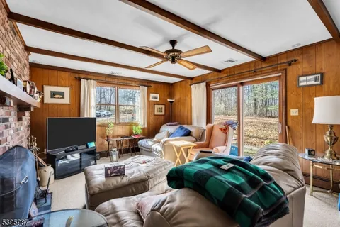 a living room with furniture a ceiling fan and a large window
