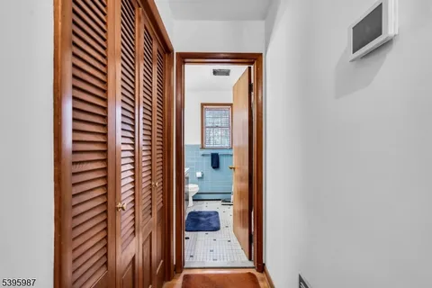 a view of a hallway with wooden floor and a bathroom