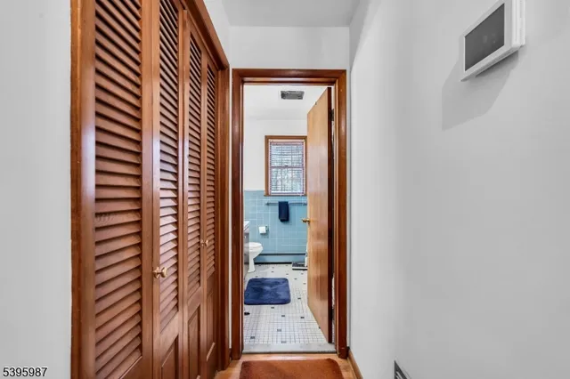 a view of a hallway with wooden floor and a bathroom