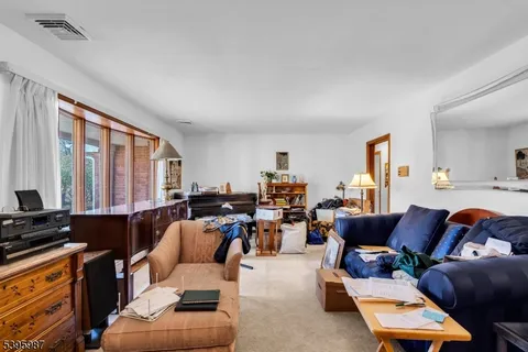 a living room with furniture two large window and a flat screen tv