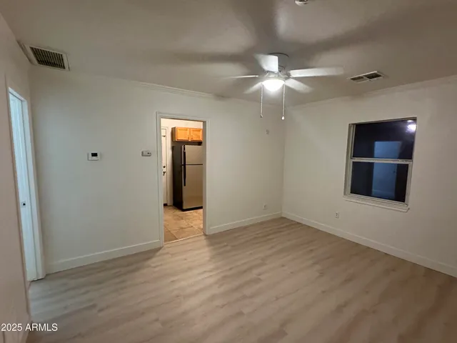 a view of an empty room with window and wooden floor
