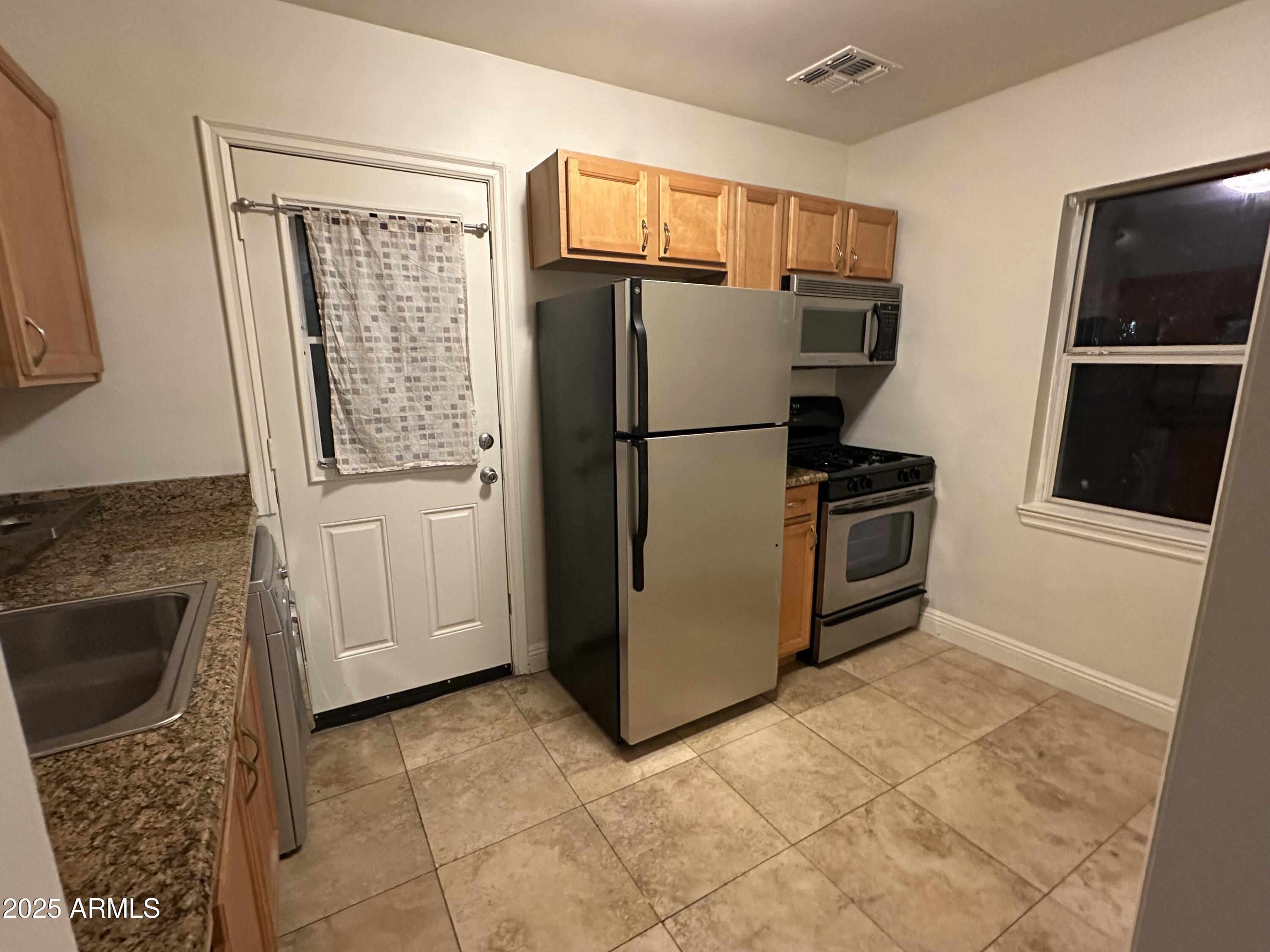 636 North 4th Avenue, Unit 3 Phoenix, AZ 85003 - Photo 6 of 8 a refrigerator freezer sitting in a kitchen with stainless steel appliances wooden cabinet and refrigerator