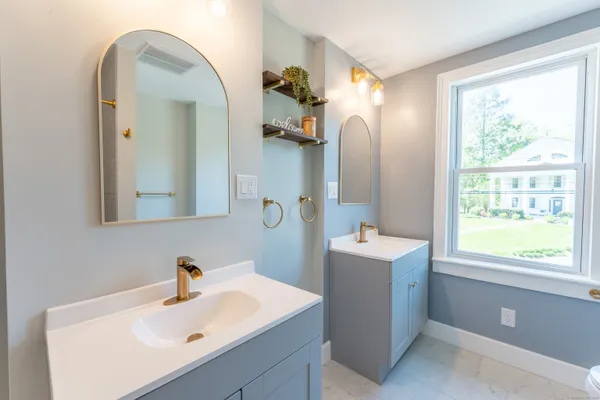 a bathroom with a sink and mirror with window