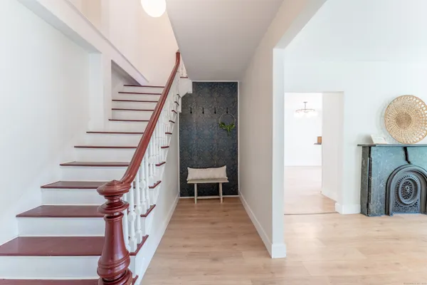 a view of a hallway to a livingroom with wooden floor and staircase