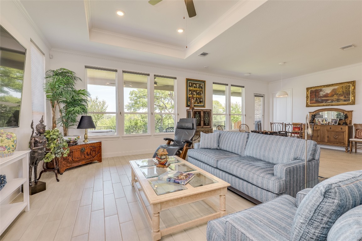 616 Climbing Rock Loop Dripping Springs, TX 78620 - Photo 10 of 35 Living room with a tray ceiling, crown molding, light wood finished floors, recessed lighting, and a ceiling fan