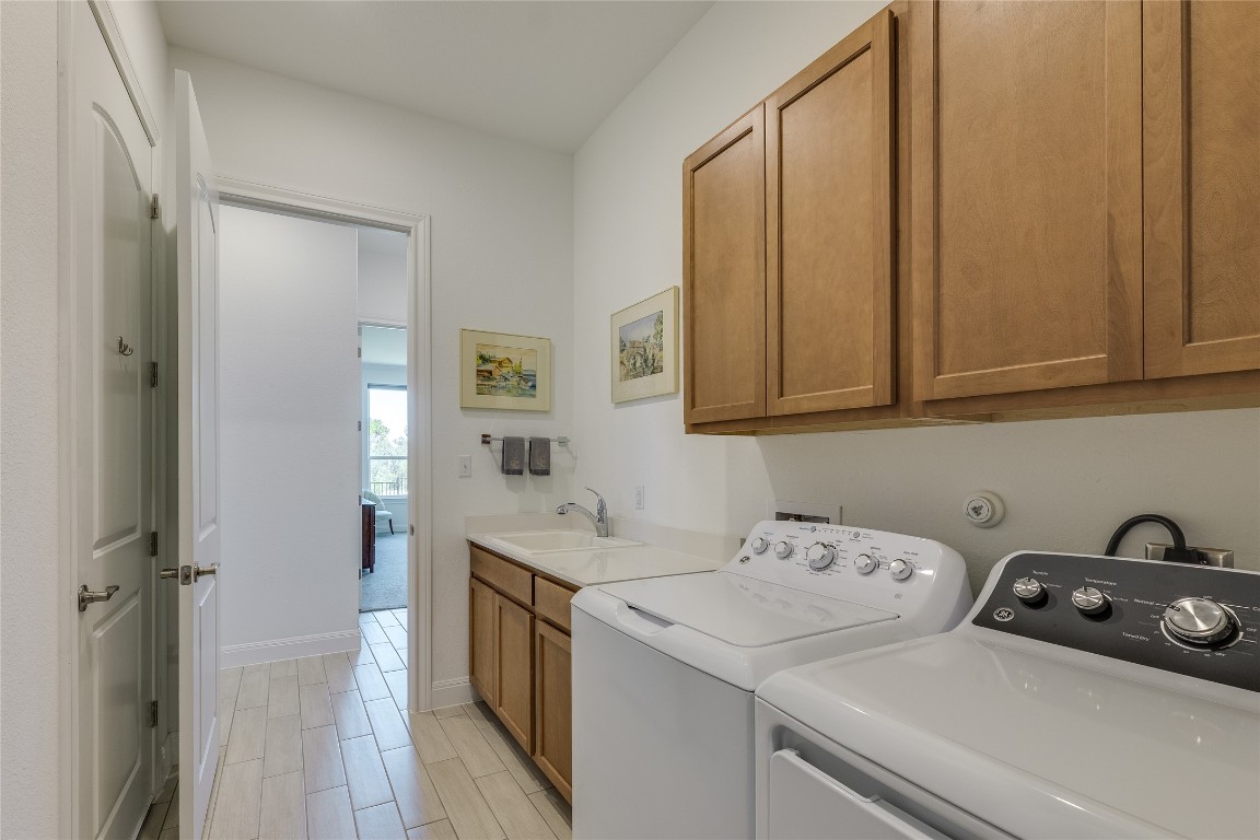 616 Climbing Rock Loop Dripping Springs, TX 78620 - Photo 17 of 35 Laundry area featuring cabinet space, washing machine and clothes dryer, and wood tiled floors