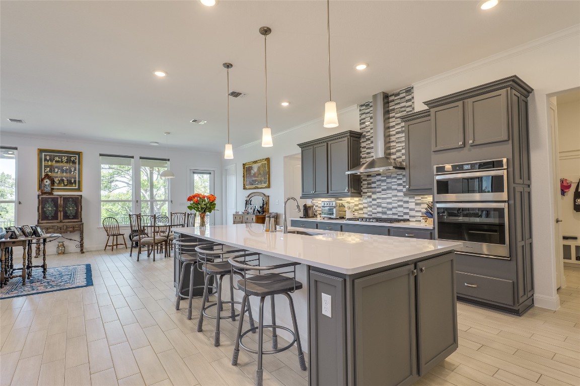 616 Climbing Rock Loop Dripping Springs, TX 78620 - Photo 4 of 35 Kitchen with decorative light fixtures, backsplash, a breakfast bar, a kitchen island with sink, and light wood-style floors