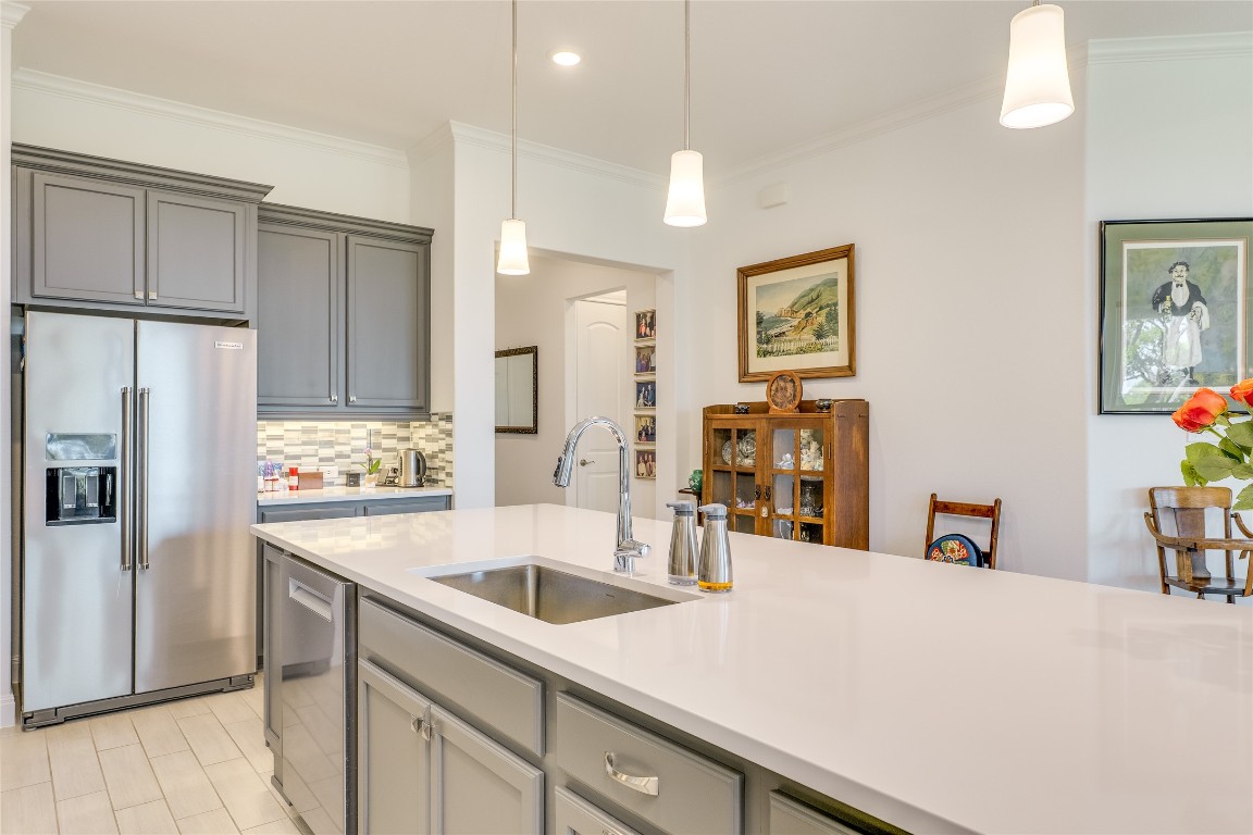616 Climbing Rock Loop Dripping Springs, TX 78620 - Photo 5 of 35 Kitchen featuring gray cabinetry, stainless steel appliances, ornamental molding, pendant lighting, and decorative backsplash