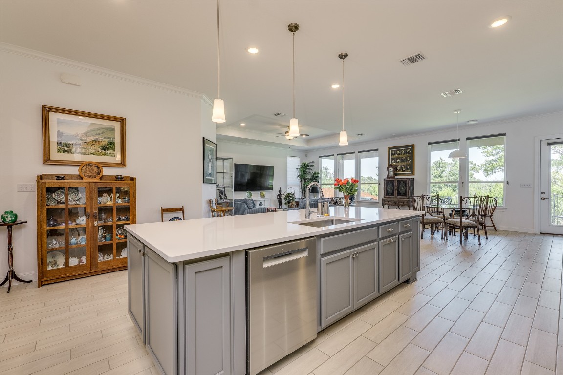 616 Climbing Rock Loop Dripping Springs, TX 78620 - Photo 35 of 35 Kitchen featuring crown molding, stainless steel dishwasher, pendant lighting, open floor plan, and a kitchen island with sink