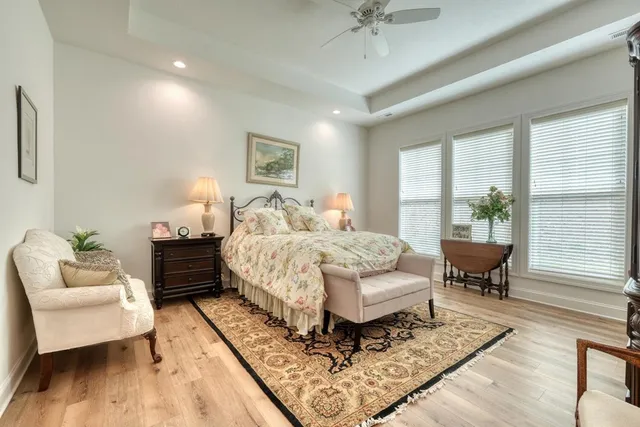 a bedroom with a bed a couch and wooden floor
