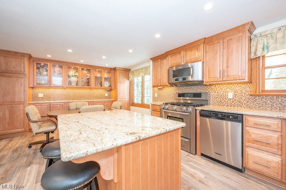 4639 Tippecanoe Road Youngstown, OH 44511 - Photo 4 of 36 Kitchen with appliances with stainless steel finishes, light stone counters, a kitchen breakfast bar, and a healthy amount of sunlight