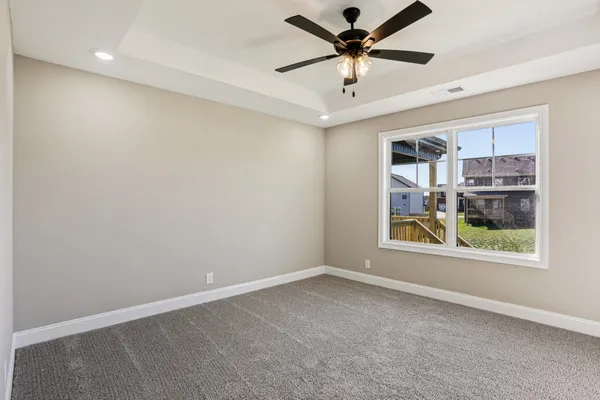 an empty room with windows and ceiling fan
