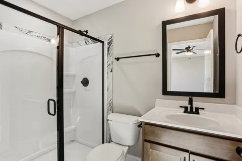 a bathroom with a sink toilet vanity and shower