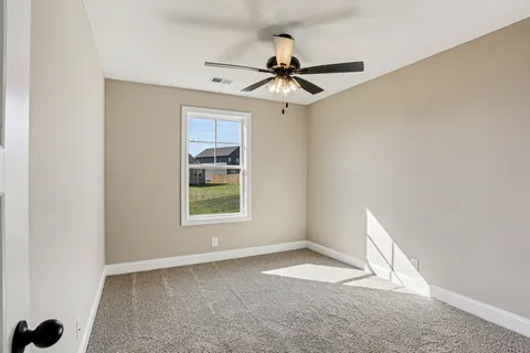 an empty room with a window and a fan