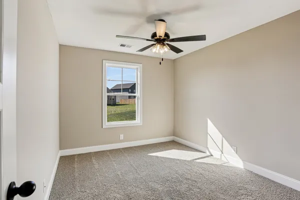 an empty room with a window and a fan