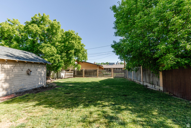 227 West 200 North Logan, UT 84321 - Photo 37 of 44 Expansive backyard featuring a lush lawn, mature trees, and a detached structure with siding
