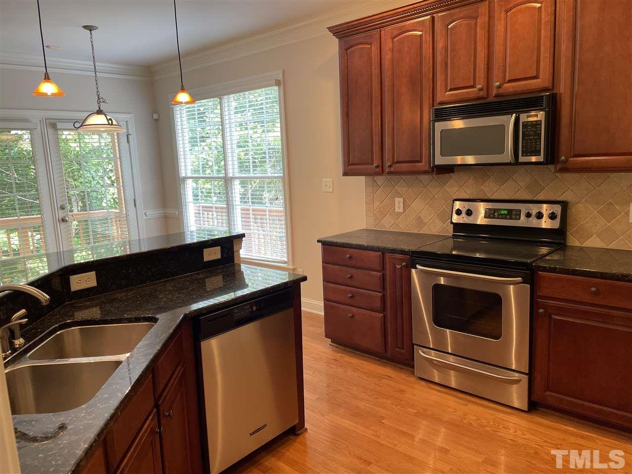 7370 Fontana Ridge Lane Raleigh, NC 27613 - Photo 13 of 27 a kitchen with granite countertop a sink a stove a microwave and cabinets