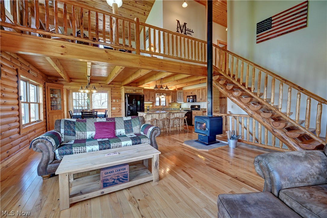 8045 McFadden Road Shreve, OH 44676 - Photo 25 of 45 Living area with a wood stove, light wood-type flooring, a high wood ceiling, and a chandelier