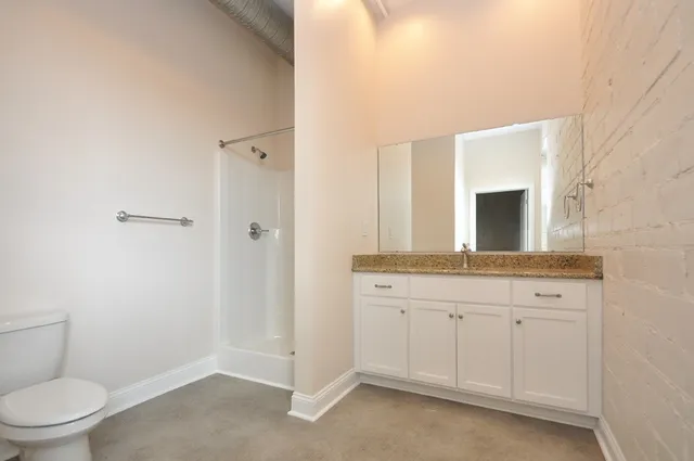 a bathroom with a granite countertop sink a toilet and a mirror