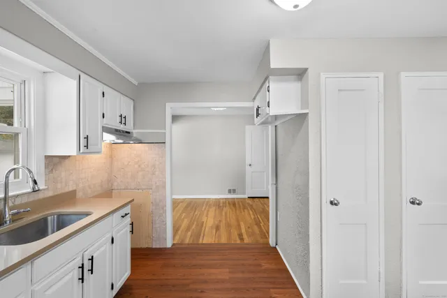 a view of an empty room with window and wooden floor