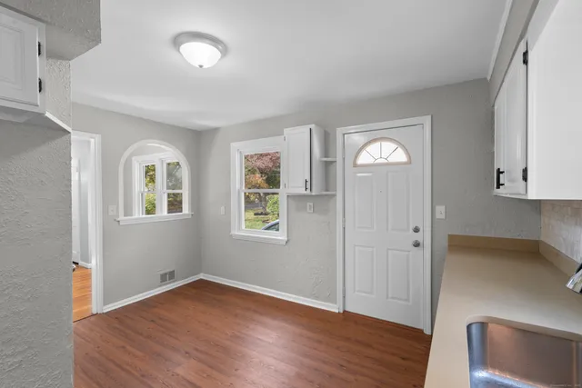 an empty room with wooden floor and windows