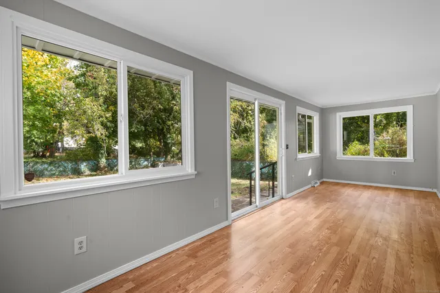 a view of an empty room with wooden floor and a window